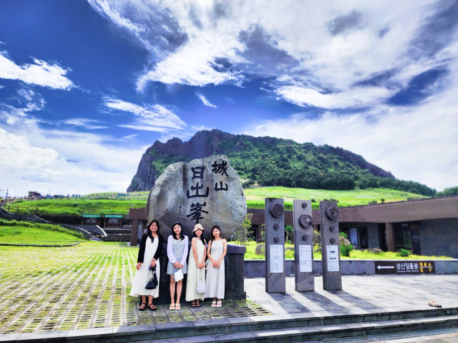 성산일출봉 표지석 너머로 보이는 녹색 봉우리