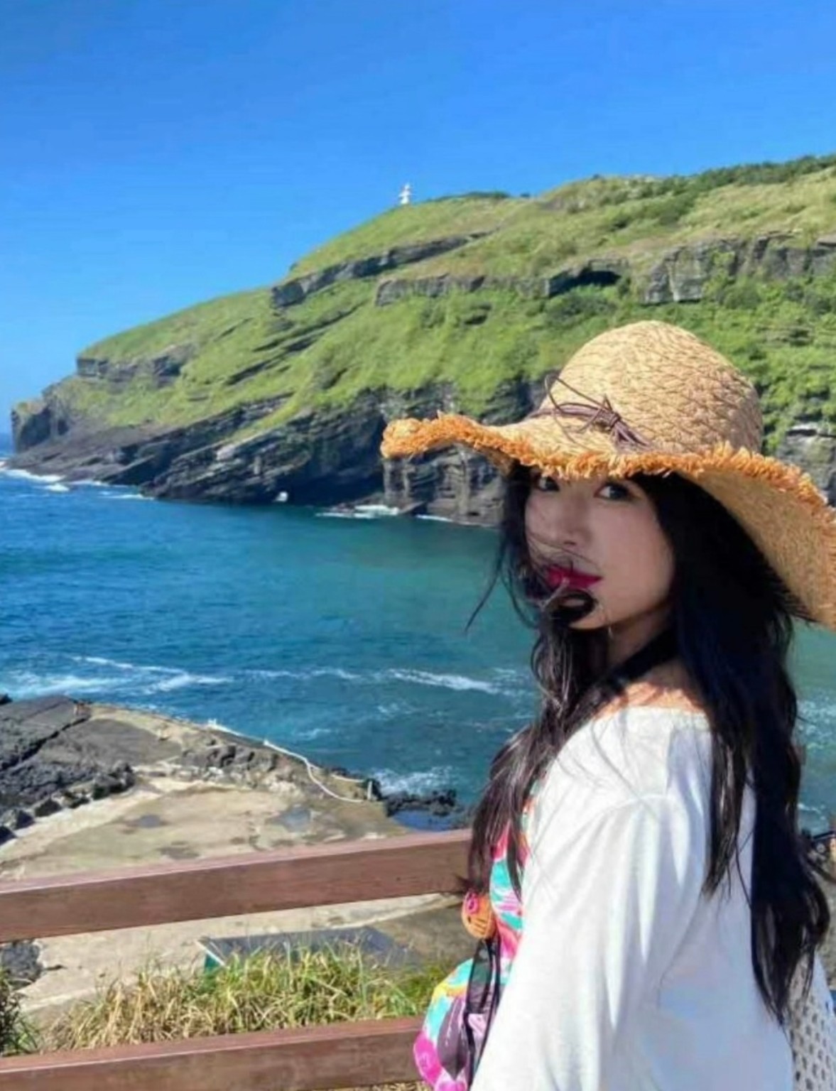 우도의 바위 절벽 앞에 선 여행객